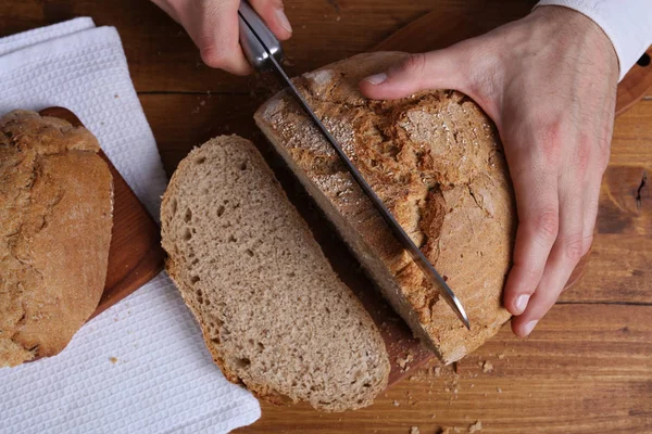 Hombre cortando sabroso pan de grano entero fresco. Concepto de alimentación saludable —  Fotos de Stock