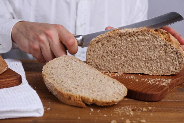 Hombre cortando sabroso pan de grano entero fresco. Concepto de alimentación saludable —  Fotos de Stock