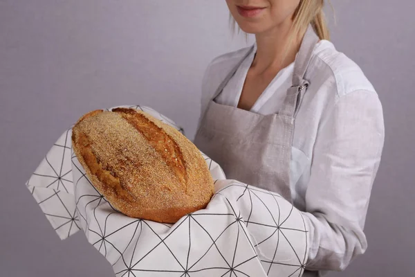 Счастливая улыбающаяся пекарь показывает буханку вкусного свежего хлеба. Кукурузный хлеб без глютена — стоковое фото