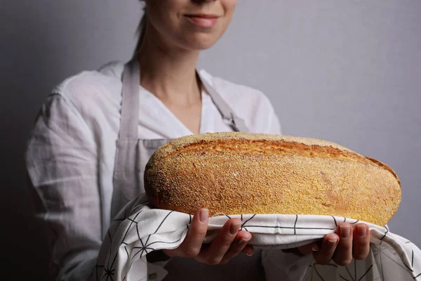 Happy smiling woman baker showing loaf of tasty fresh bread. Gluten free cornbread