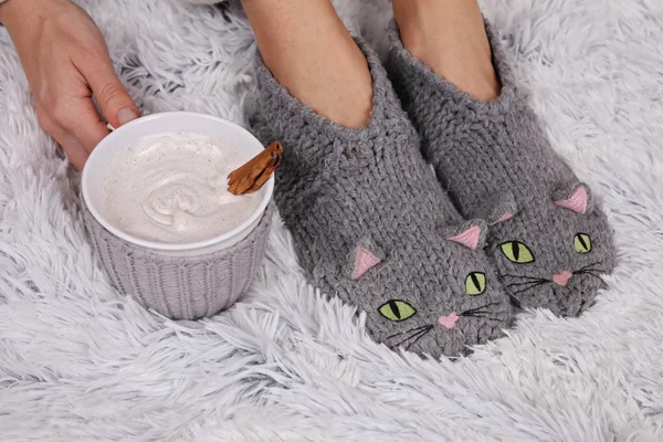 Woman wearing cozy warm wool socks and drinking cacao, close up. Warmth concept. Winter clothes. Soft, comfy lifestyle.