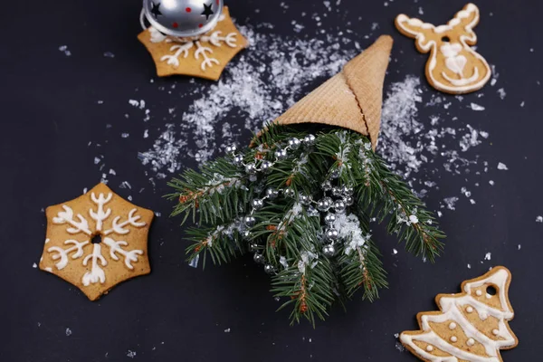 华夫格锥圣诞 wirh 树枝和姜饼干在深色背景上的。新的一年概念背景 — 图库照片