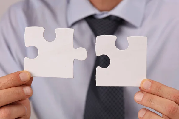 Soluciones empresariales, concepto de asociación. Empresario sosteniendo dos piezas de un rompecabezas en blanco — Foto de Stock