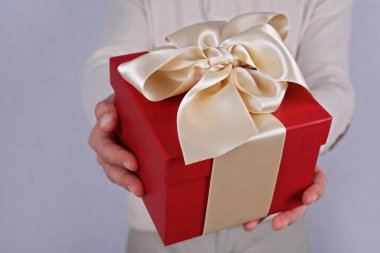 Kırmızı mevcut beyaz kurdele ile tutan adam kapatın. Hediye kutusu. Doğum günü, yılbaşı, Sevgililer günü, 8 Mart, Noel kavramı.