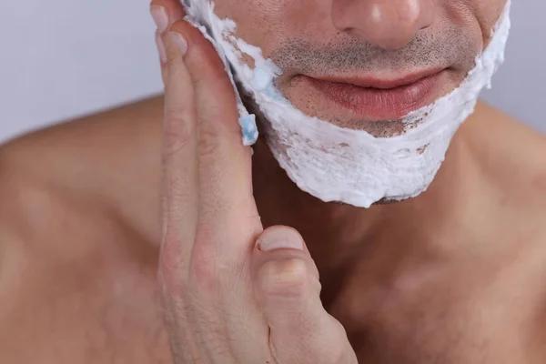 Atractivo sonriente Hombre poniendo espuma de afeitar en su cara de cerca. Hombres cuidado de la piel concepto . — Foto de Stock