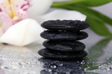 Spa arka plan. Volkanik kayalar, bambu ve yağmur damlaları ile yansıtıcı arka plan üzerinde orkide. Gevşeme, vücut bakım tedavisi, spa, sağlık kavramı