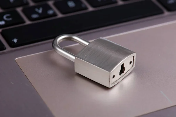 Padlock on silver aluminium notebook, laptop. Internet, web safety, privacy and security concept.
