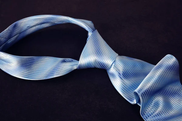 Niebieski elegancki krawat jedwabny na czarnym tle. — Zdjęcie stockowe