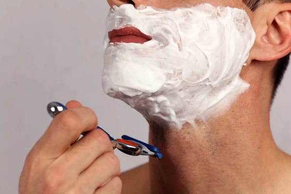 Man shaving his face with the razor blade through shave foam. Men skin care concept. Stock Picture