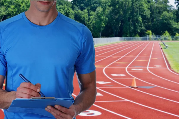 Treinador atlético com plano de treino perto das pistas. Esporte, fitness e conceito de estilo de vida saudável . — Fotografia de Stock