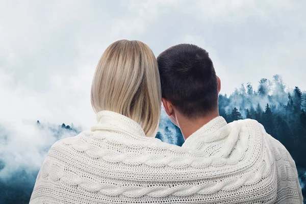 Pareja enamorada cubierta de manta disfrutando de vistas a la montaña en vacaciones de invierno — Foto de Stock