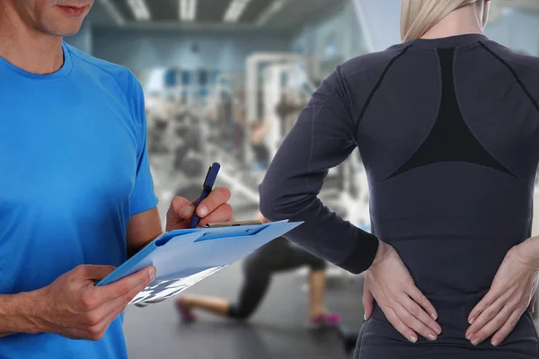 Femme sportive avec douleur au dos dans la salle de gym. Sports pratiquant des blessures. Réadaptation et exercice pour un dos sain — Photo