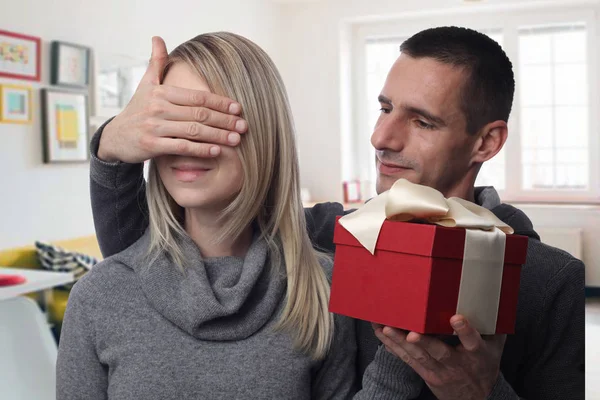 Pareja feliz enamorada. Hombre joven cubriendo los ojos de su novia mientras le da un regalo. Cumpleaños, Año nuevo, San Valentín, 8 de marzo, concepto de Navidad . — Foto de Stock