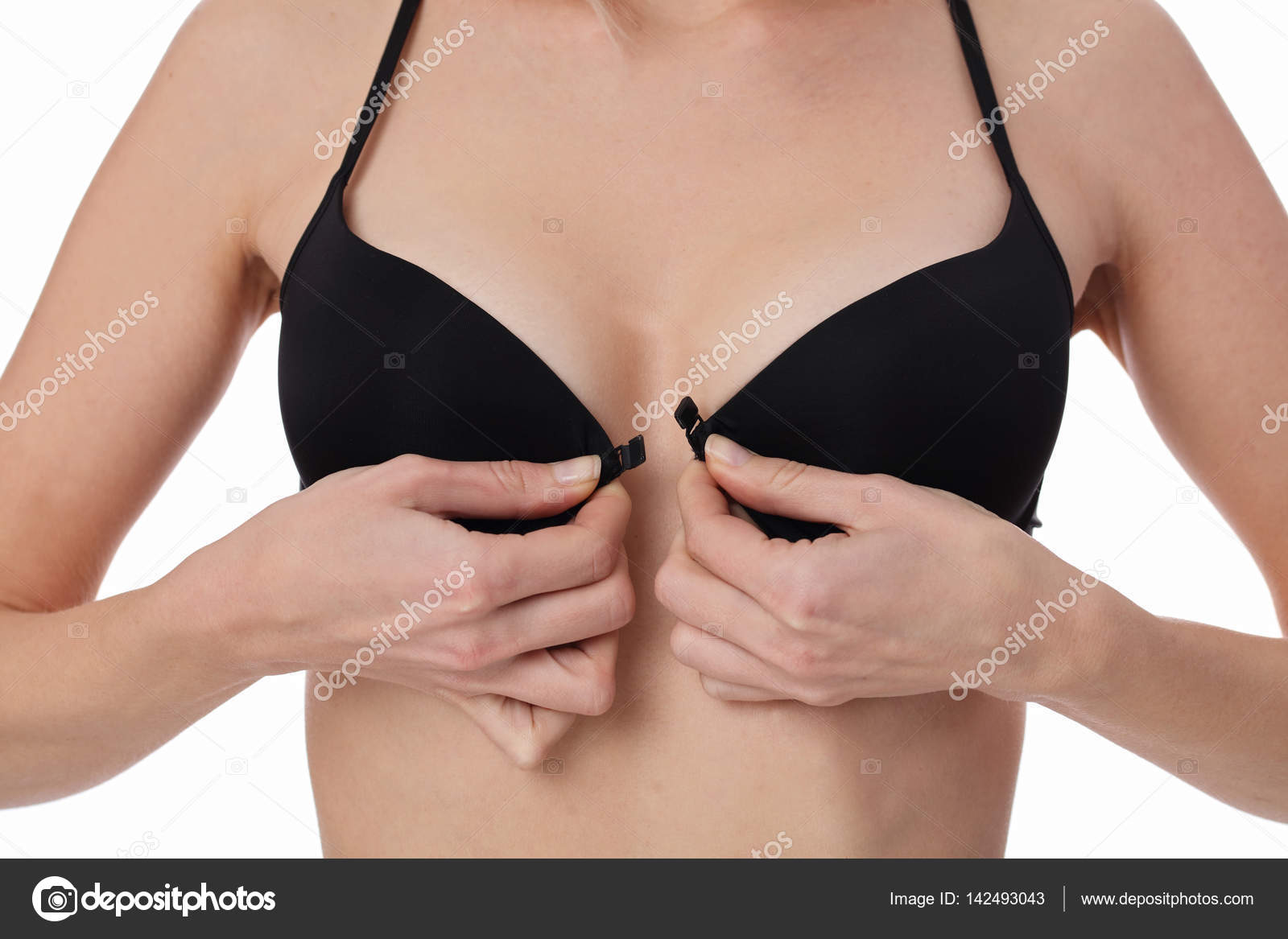 Woman taking off bra, wearing black underwear isolated on white background.
