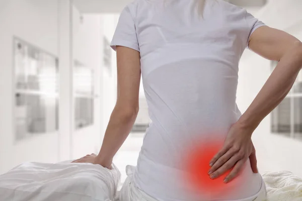 Vrouw die lijden aan rugpijn thuis in de slaapkamer. Ongemakkelijke matras en kussen oorzaken rugpijn. — Stockfoto