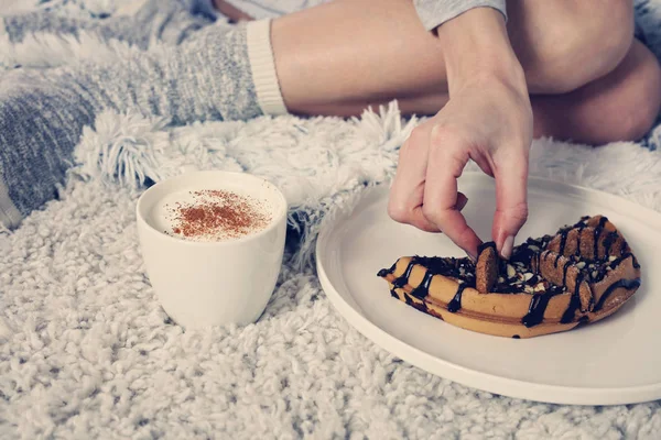 Mujer con calcetines acogedores de lana cálida relajante en casa, beber cacao, disfrutar de su desayuno, gofres belgas con chocolate negro, concepto de la mañana de invierno. Estilo de vida suave y cómodo . —  Fotos de Stock