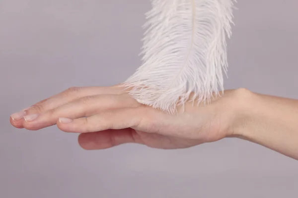 Женщина дотрагивается до своей гладкой идеальной кожи руки после косметической процедуры с пером . — стоковое фото