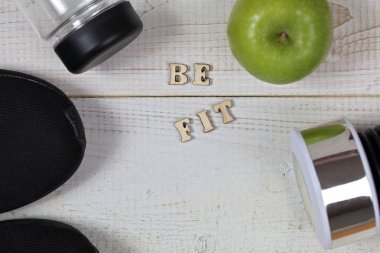 Fitness motivasyon uygun. İlham tırnak. Spor öğeleri, halter, elma, şişe su beyaz ahşap zemin üzerinde. Sağlıklı yaşam konsepti.