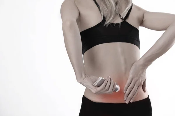 Mulher que sofre de dor nas costas aplicando creme de alívio da dor. Esporte exercício lesão . — Fotografia de Stock