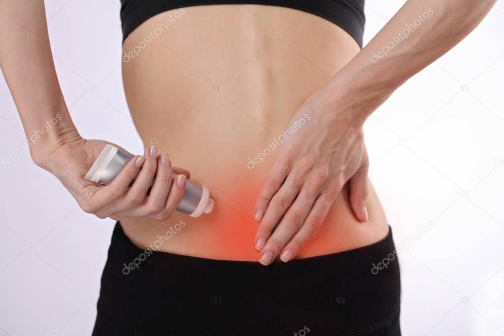 Woman suffering from back pain applying pain relief cream . Spor