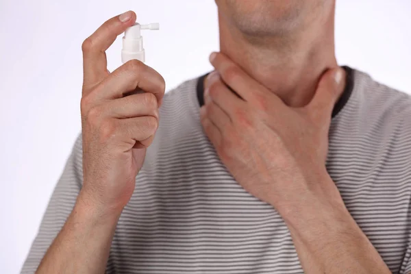 Людина, яка використовує спрей для горла для усунення інфекції в горлі, допомагає полегшити біль. Охорона здоров'я та медична концепція — стокове фото