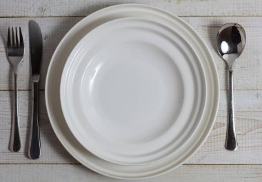 Boş tabak çatal, kaşık ve bıçak rustik ahşap masa üzerinde. Minimalist arka plan