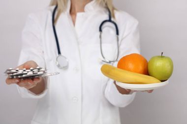Sağlık ve sağlıklı beslenme, beslenme denge kavramı. Erkek tıp hapları ve elma tutan doktor