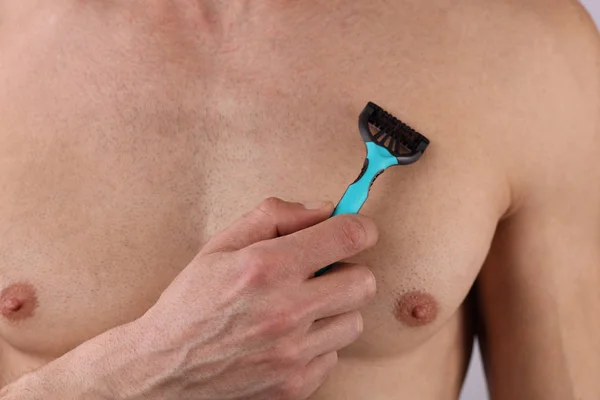 Male depilation. Young attractive muscular man using razor to remove hair from his body — Stock Photo, Image