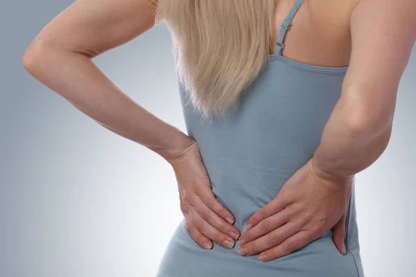 Rückenschmerzen. Sportliche Fitness-Frau reibt die Muskeln ihres unteren Rückens. Sportliche Betätigung. — Stockfoto