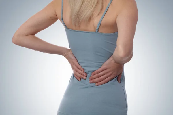 Douleur au dos. Femme de fitness athlétique frottant les muscles du bas du dos. Sports exerçant une blessure. — Photo