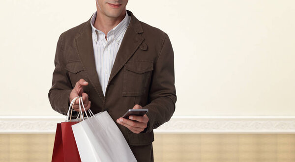 Man shopping. Male holding shopping bags and using cellphone. Online shopping concept.