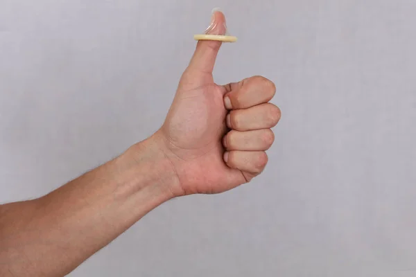 Człowiek posiadający prezerwatywa i pokazując kciuk w górę. Antykoncepcja, zapobieganie choroby przenoszone drogą płciową. Koncepcja zdrowia seksualnego. — Zdjęcie stockowe