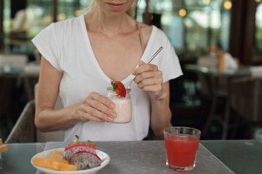 Çilekli yoğurt ve meyve yemek kahvaltı için mutlu gülümseyen kadın. Sağlıklı beslenme ve yaşam tarzı kavramı