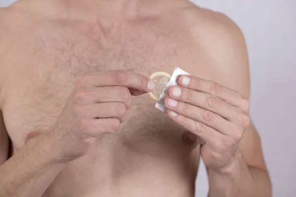 Мужчина держит презерватив за руку. Профилактика заболеваний, передающихся половым путем. Здравоохранение и профилактика ЗППП . — стоковое фото