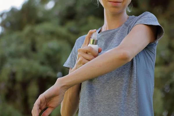 Mosquito repellent. Woman using insect repellent cream outdoors.