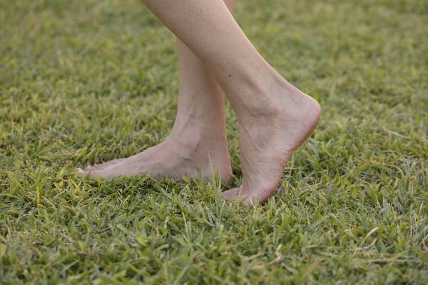Jovem descalça desfrutando de relaxamento andando em grama verde fresca ao ar livre no parque ensolarado primavera. Barefootismo — Fotografia de Stock