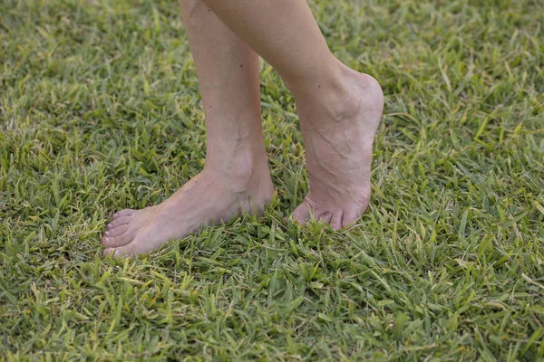 Jovem descalça desfrutando de relaxamento andando em grama verde fresca ao ar livre no parque ensolarado primavera. Barefootismo — Fotografia de Stock