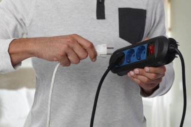 Enerji tasarrufu kavramı. Elektrik güç uzatma kablosu tutan adam.