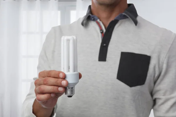 Energy efficiency, saving concept. Man holding light bulb.