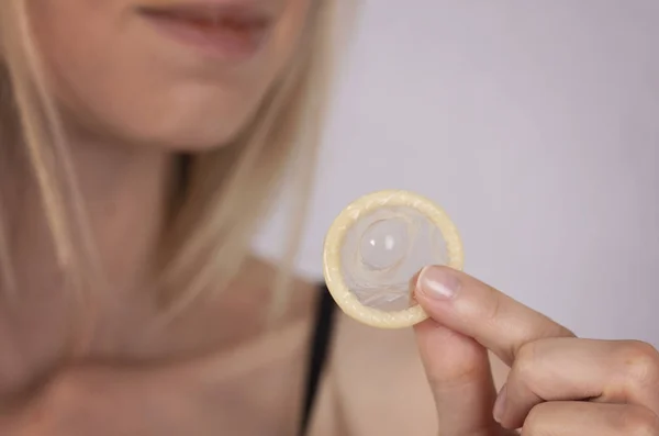 Frau mit Kondom in Großaufnahme. Empfängnisverhütung, Prävention sexuell übertragbarer Krankheiten. Konzept der sexuellen Gesundheit. — Stockfoto