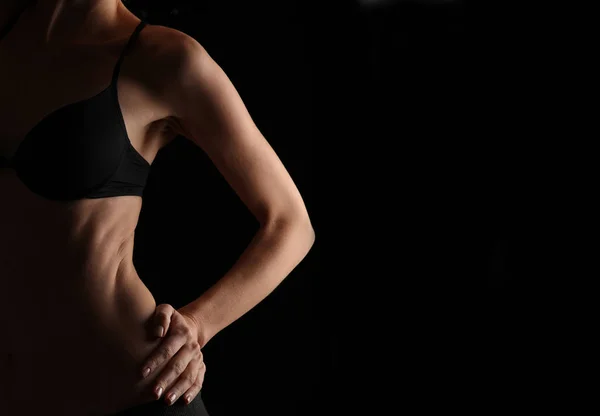 Wunderschöner weiblicher Athletenkörper, perfekte Bauchmuskeln und Schräglagen. starke Sportlerin auf schwarzem Hintergrund, zurückhaltendes Image — Stockfoto