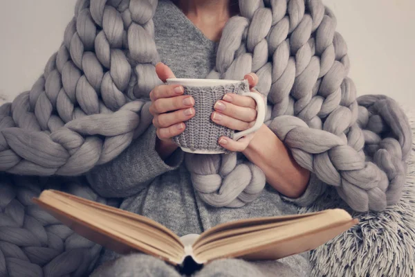 Acogedora mujer cubierta de cálida manta de lana merino suave leyendo un libro. Relájate, estilo de vida confortable . —  Fotos de Stock