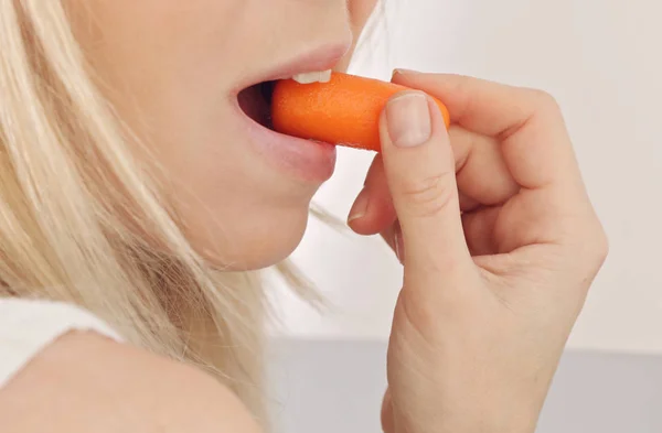 Woman eating carrot close up. Cooking and healthy eating concept Stock Picture