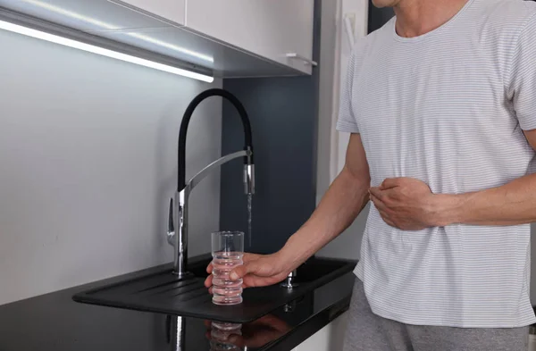 Mann leidet unter Magenschmerzen, nachdem er Leitungswasser getrunken hat. bakteriologisch geeignetes Wasser-, Sanitär- und Hygienekonzept. — Stockfoto
