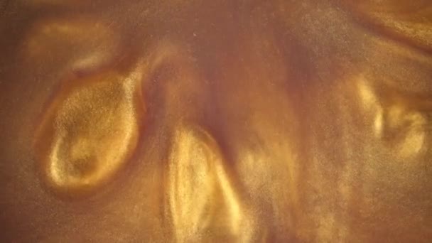 4 k film. Bläcket i vatten. Guld bläck reagerar i vatten skapa abstrakt bakgrund. — Stockvideo