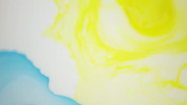 Запись 4К. Чернила в воде. Синие и желтые чернила реагируют в воде, создавая абстрактный фон . — стоковое видео