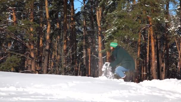 Медленная съемка. Красивая молодая девушка бросает снежок в лесу — стоковое видео