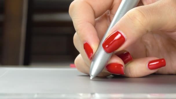 Imagens 4K. Mãos femininas com manicure vermelho usando caneta comprimido. Close-up — Vídeo de Stock