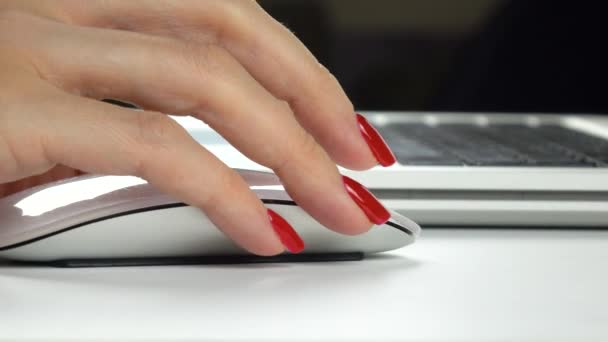 Imágenes de 4K. Las mujeres de la mano con manicura roja utilizando un ratón de ordenador inalámbrico. Primer plano — Vídeo de stock