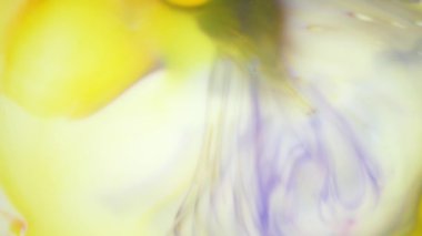 Suda mürekkep. Sarı ve mor mürekkep suda reaksiyona girerek soyut bir arkaplan oluşturuyor.